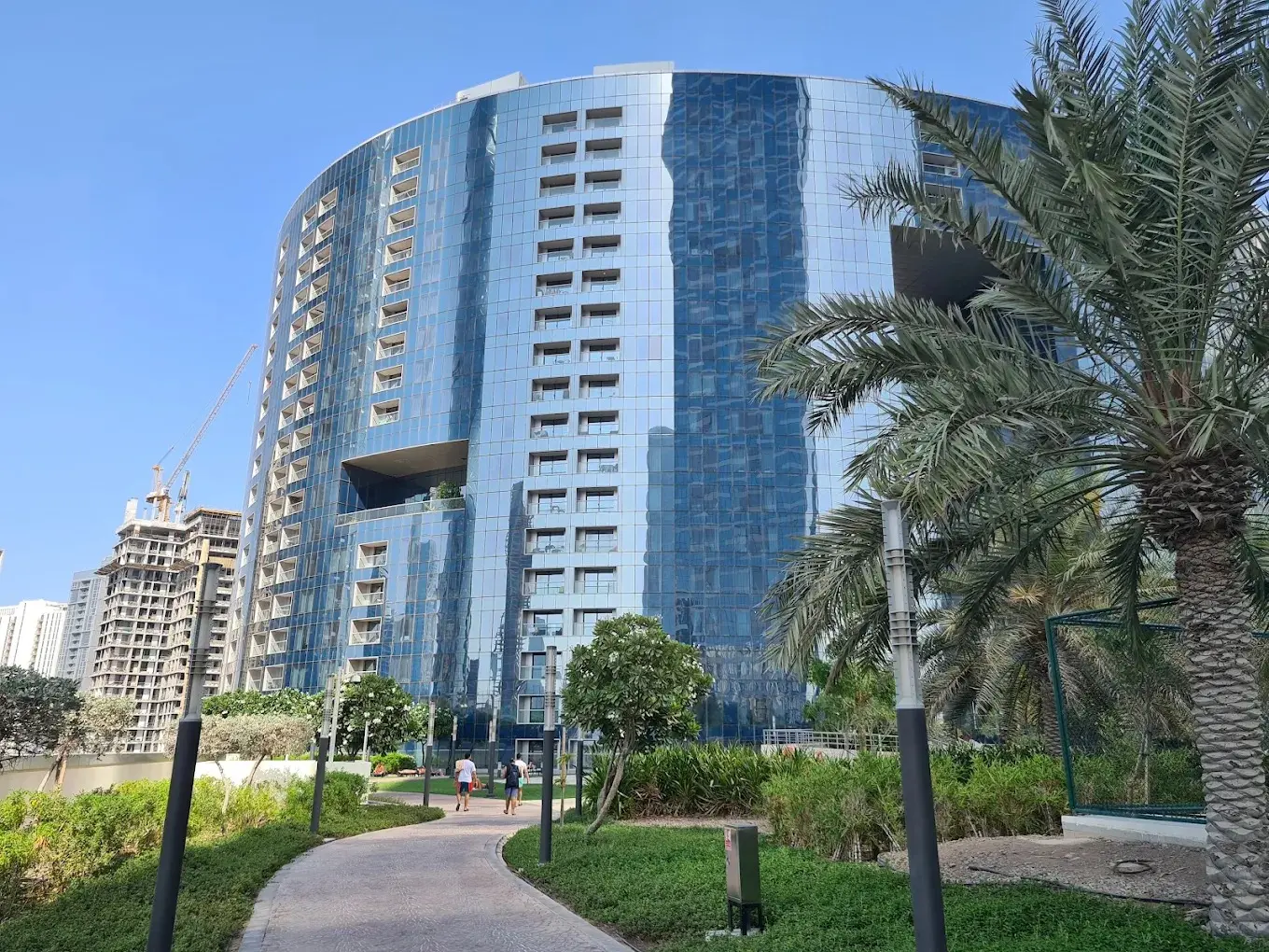 Exterior leisure area of The Arc Tower, featuring tropical swimming pools, lazy river, and residential tower background.