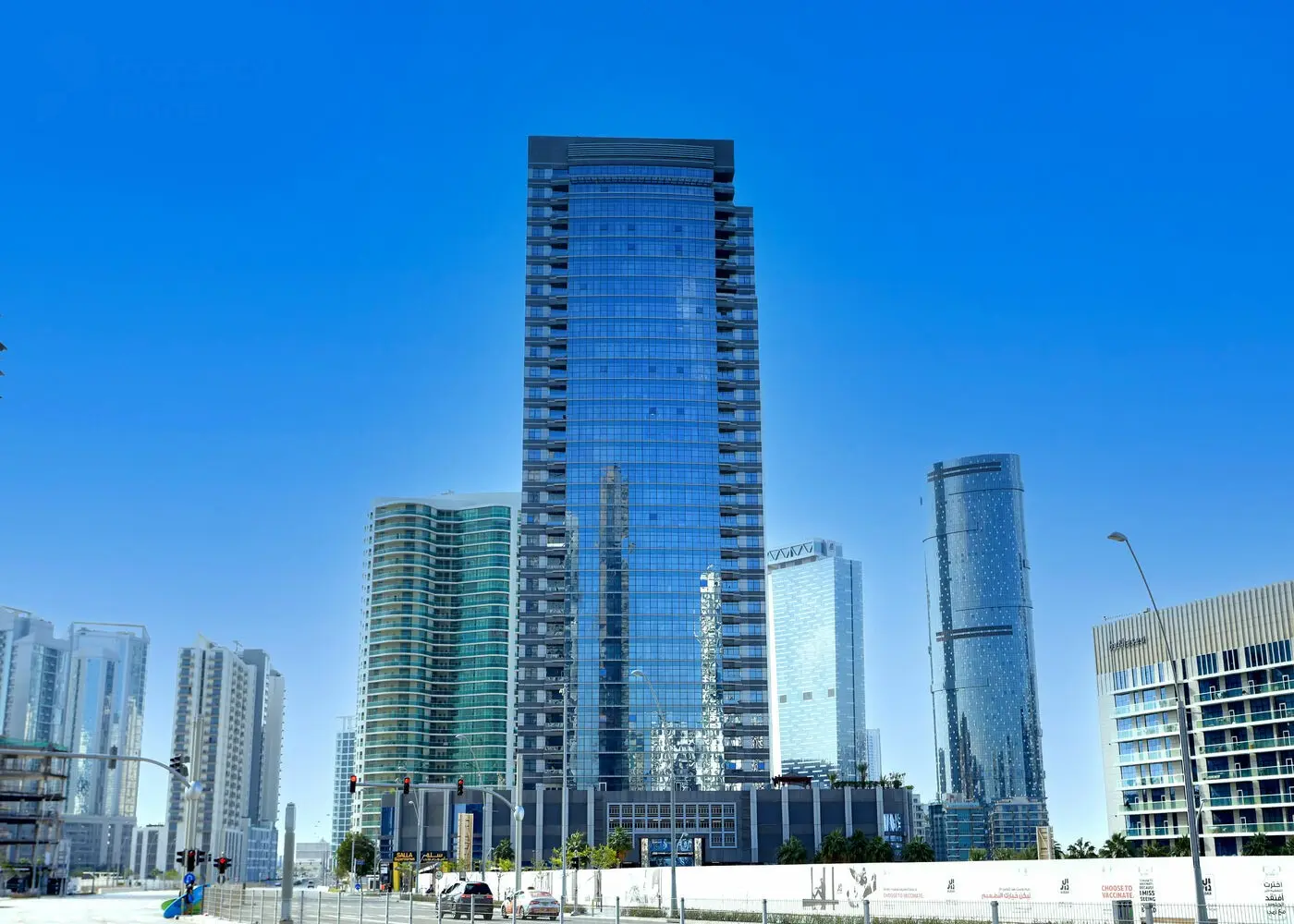 Exterior street-level view of Al Wifaq Tower luxury residential building with ground-floor retail in Shams Abu Dhabi, UAE.
