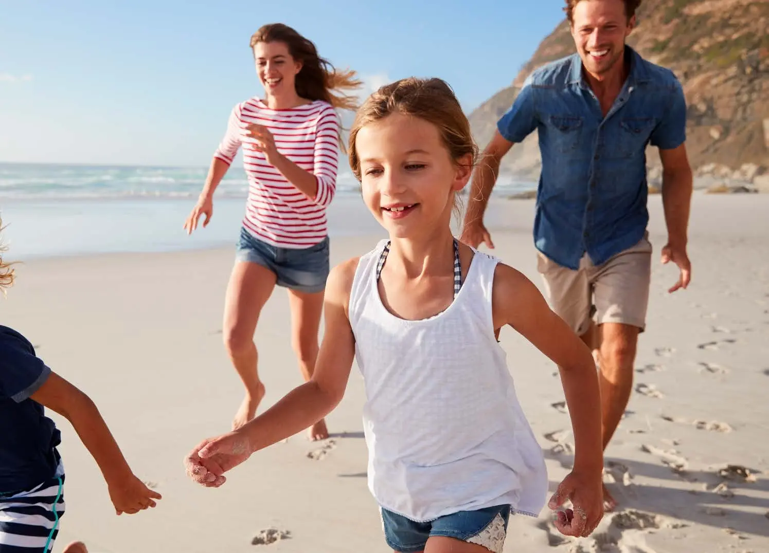 Joyful family running along the white sandy shoreline bordering luxury community Capeside Marina Residences Siniya Island.