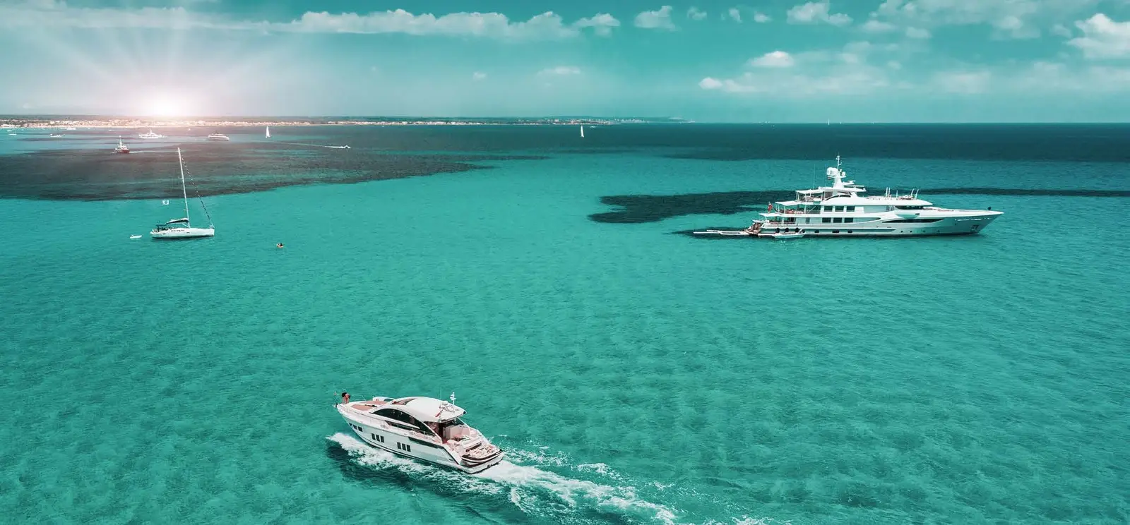 Luxury yachts sailing across shimmering emerald coastal waters fronting Capeside Marina Residences at Sobha Siniya Island Umm Al Quwain