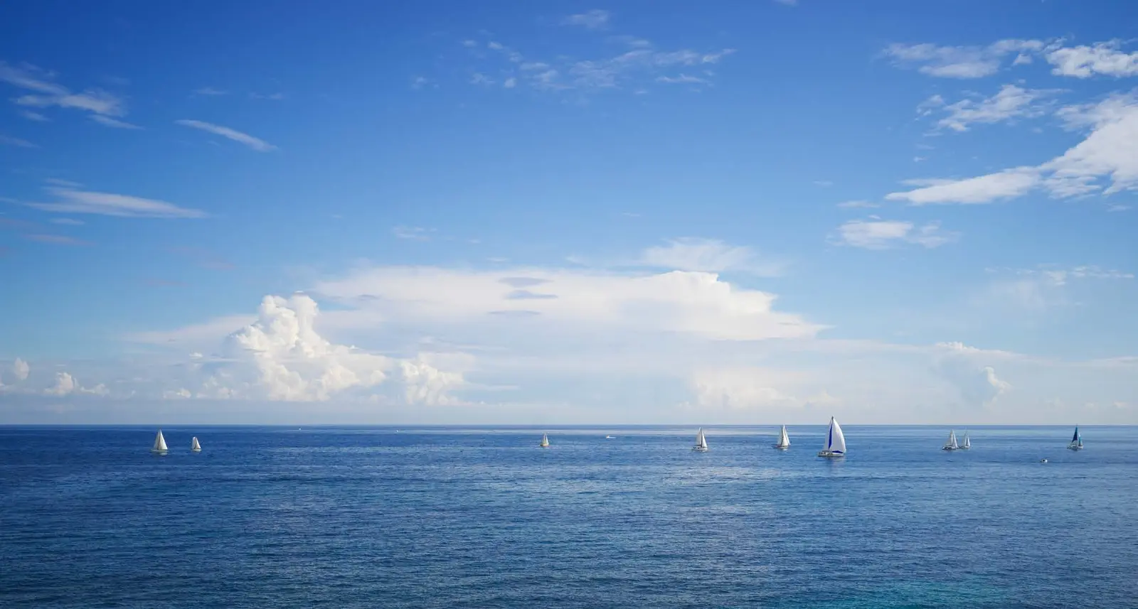 Panoramic open blue sea horizons with sailing boats bordering coastal paradise at Capeside Marina Residences Siniya Island.