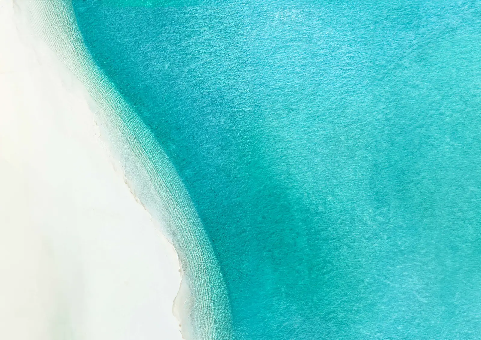 Pristine turquoise sea waters and white sand coastline surrounding Capeside Marina Residences at Sobha Siniya Island Umm Al Quwain.