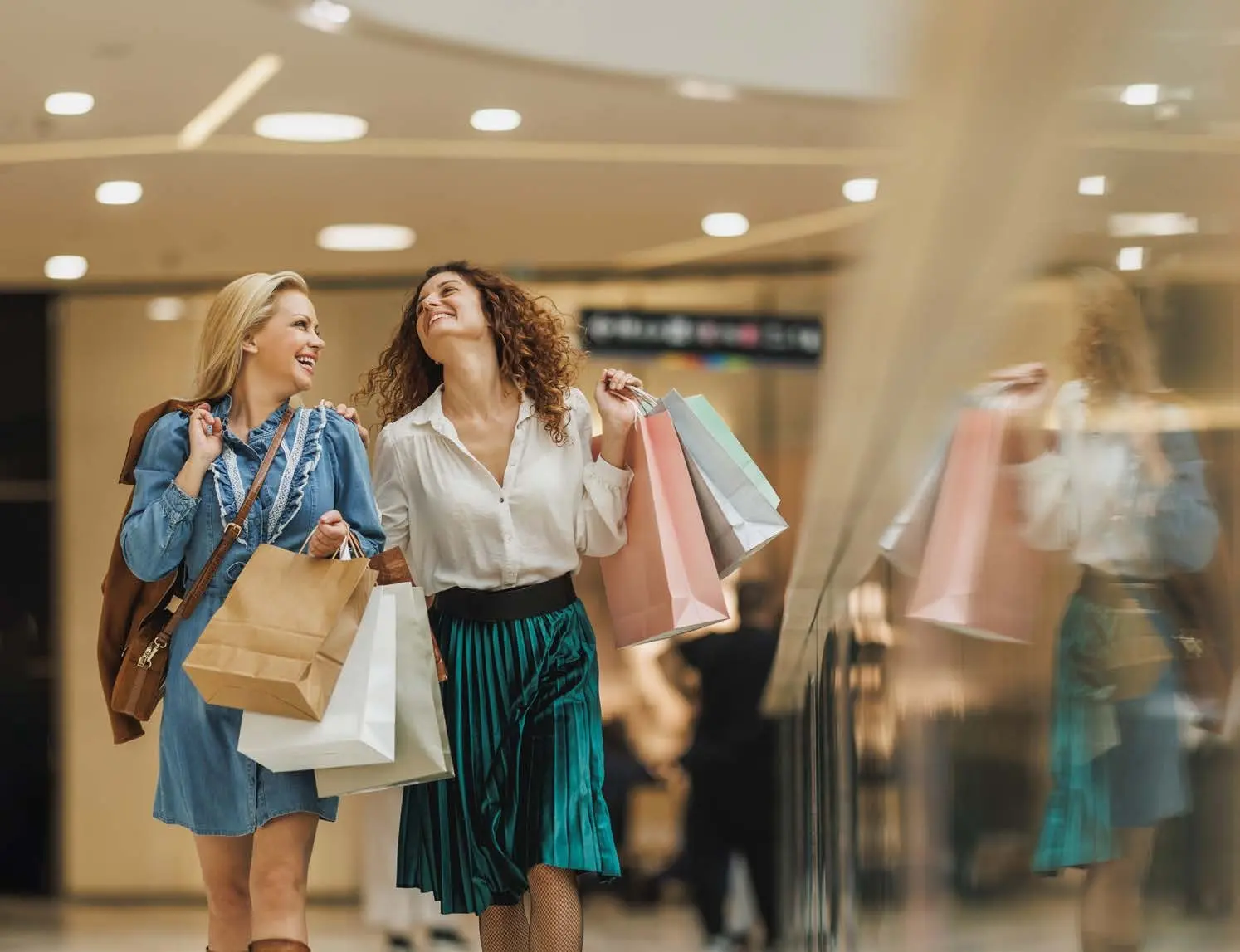 Shoppers walking through premium retail mall and fashion promenade at Capeside Marina Residences on Sobha Siniya Island.