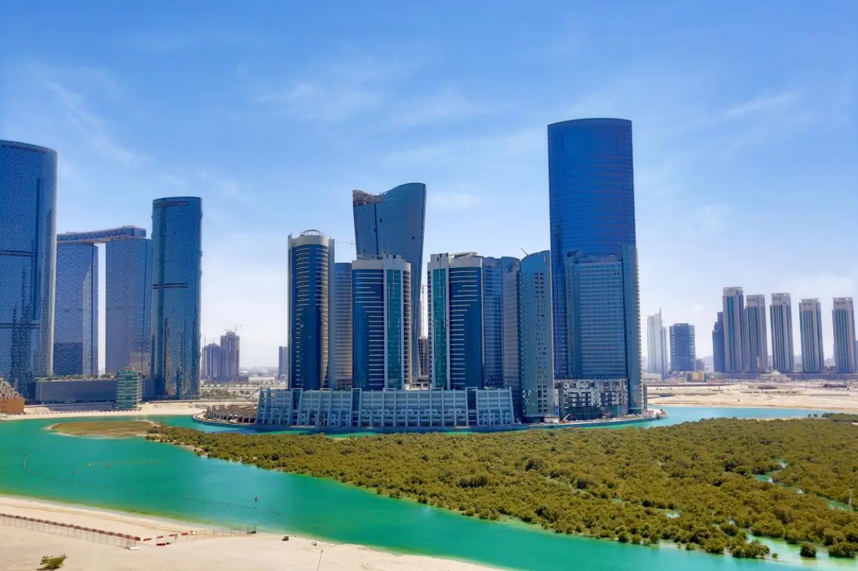 Modern Abu Dhabi waterfront skyline at Marina Spirit City of Lights with sleek glass towers rising above lush mangroves.
