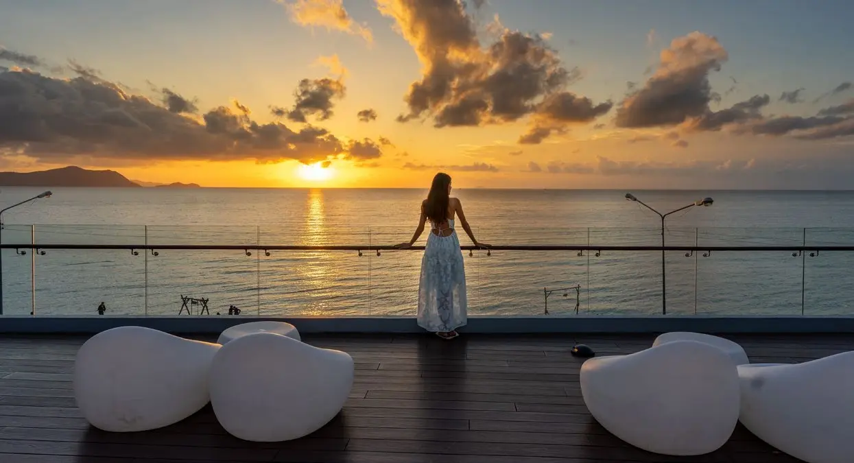 Woman admiring scenic sunset ocean horizons from the outdoor entertainment terrace at Bayfront Marina Residences Umm Al Quwain.